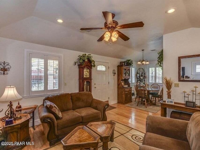 living room with ceiling fan with notable chandelier, vaulted ceiling, recessed lighting, and light wood-style floors