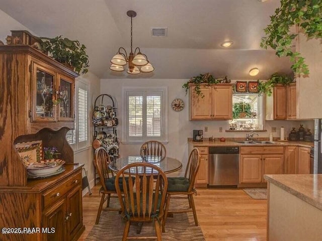 kitchen with a sink, vaulted ceiling, stainless steel dishwasher, a notable chandelier, and light wood-type flooring