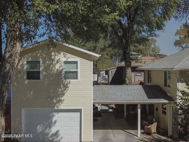 view of home's exterior featuring a garage and roof with shingles