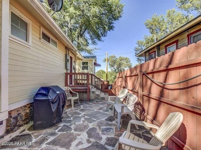 view of patio with fence and a grill