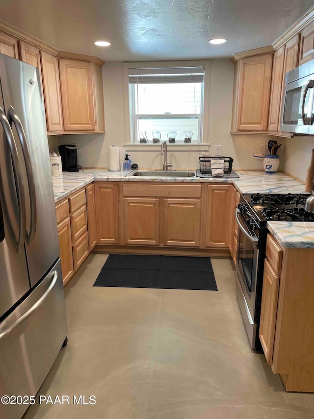 kitchen with light stone countertops, light brown cabinets, stainless steel appliances, and a sink