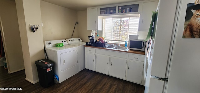 laundry room featuring washing machine and clothes dryer, cabinets, sink, and dark wood-type flooring
