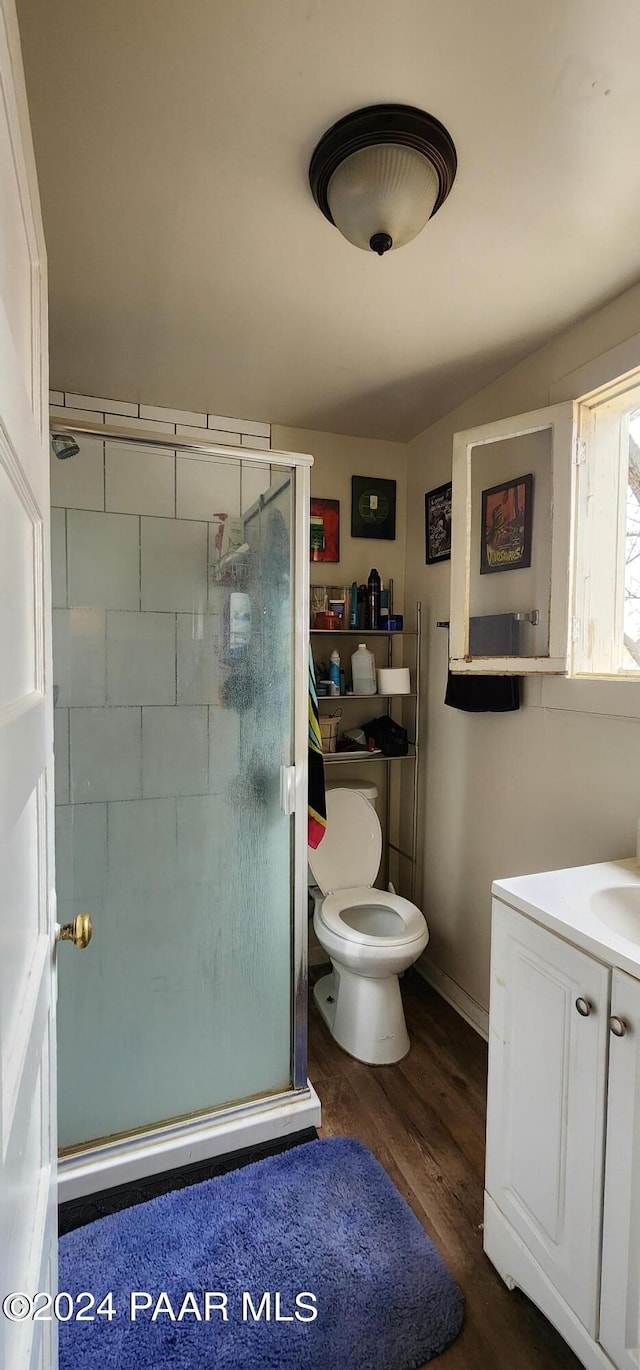 bathroom featuring hardwood / wood-style floors, vanity, toilet, and a shower with door