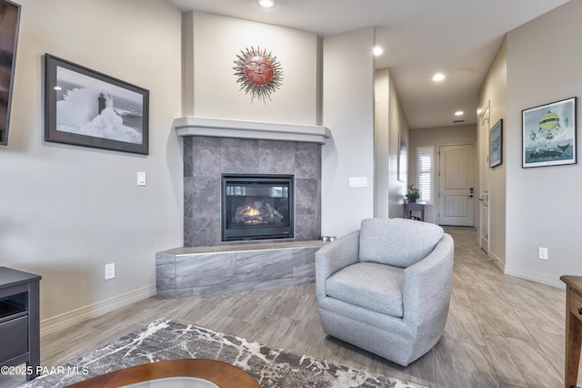 living room featuring a tile fireplace, baseboards, and recessed lighting
