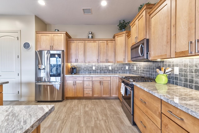 kitchen featuring recessed lighting, stainless steel appliances, decorative backsplash, visible vents, and light stone countertops