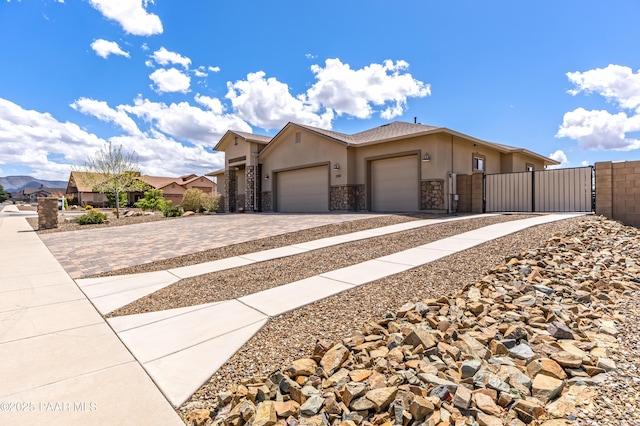 view of front of property featuring stone siding, stucco siding, fence, decorative driveway, and a garage