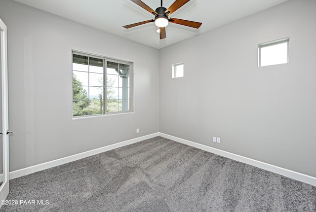 unfurnished room with ceiling fan, dark carpet, and a wealth of natural light