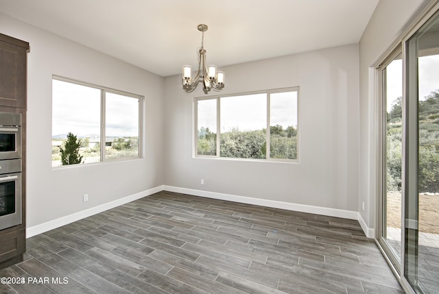 unfurnished dining area with a notable chandelier and dark hardwood / wood-style flooring