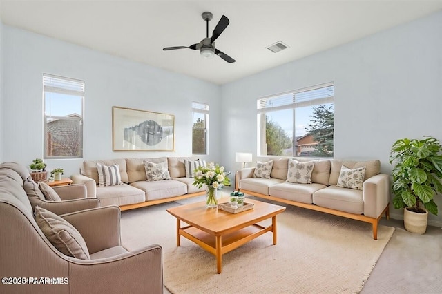 carpeted living area featuring visible vents and a ceiling fan