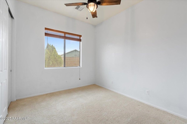 carpeted empty room featuring ceiling fan, visible vents, and baseboards