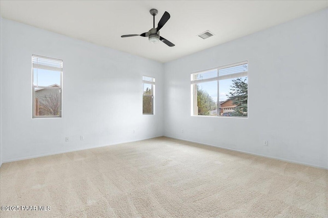 carpeted spare room featuring visible vents and a ceiling fan