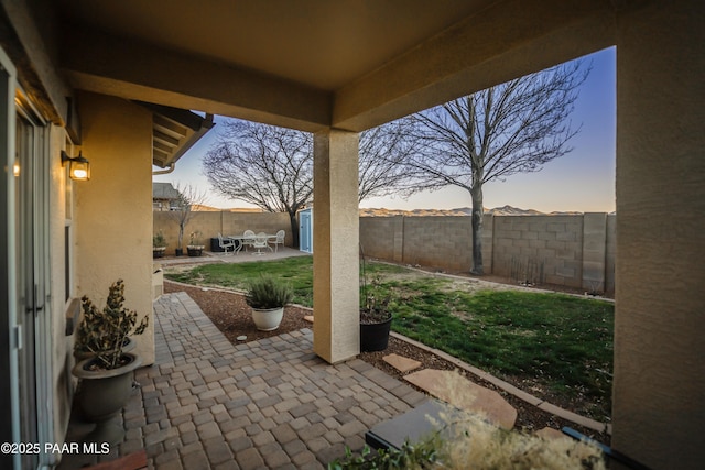 patio terrace at dusk featuring a shed