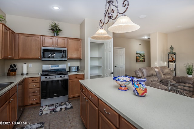 kitchen with dark tile patterned flooring, pendant lighting, sink, built in features, and appliances with stainless steel finishes