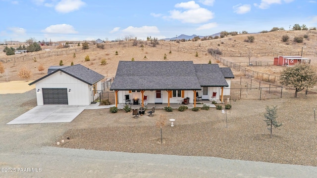 modern inspired farmhouse featuring covered porch, a mountain view, a garage, and an outbuilding