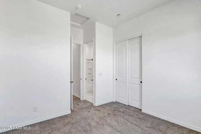 unfurnished bedroom featuring light carpet, connected bathroom, and a closet