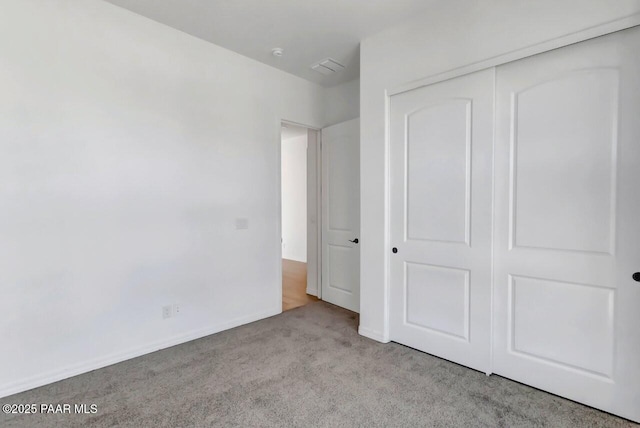 unfurnished bedroom with light carpet and a closet