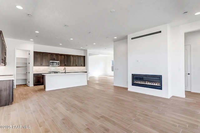 unfurnished living room featuring sink and light hardwood / wood-style flooring