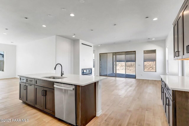 kitchen with sink, a kitchen island with sink, stainless steel dishwasher, and dark brown cabinetry