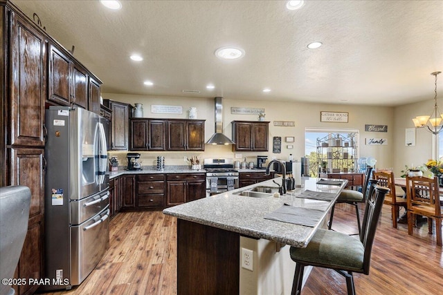 2360 W Bridle Path Rd, Prescott, AZ 86305 - kitchen featuring stainless steel appliances, a sink, wall chimney exhaust hood, a breakfast bar area, and dark brown cabinetry