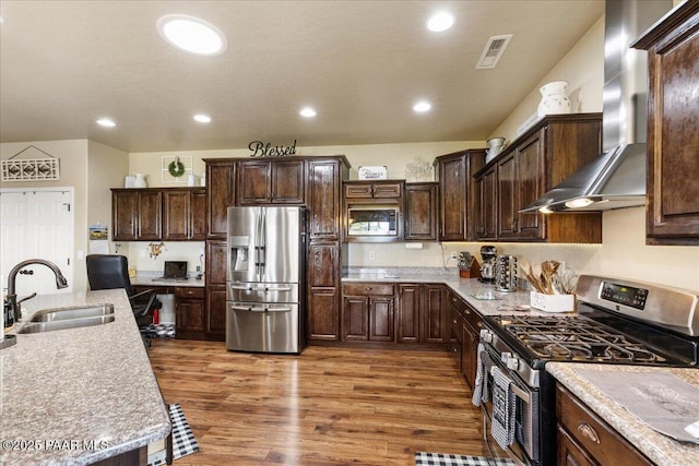 2360 W Bridle Path Rd, Prescott, AZ 86305 - kitchen with stainless steel appliances, a sink, wall chimney exhaust hood, dark brown cabinets, and wood finished floors
