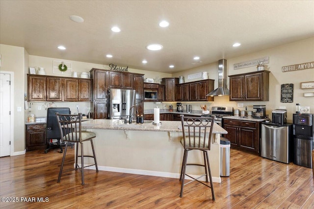 2360 W Bridle Path Rd, Prescott, AZ 86305 - kitchen featuring appliances with stainless steel finishes, wall chimney range hood, wood finished floors, a large island, and recessed lighting