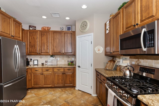 kitchen featuring decorative backsplash, stainless steel appliances, and light stone counters