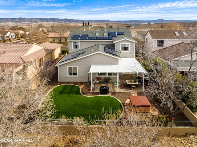 rear view of property with a lawn, a mountain view, and solar panels