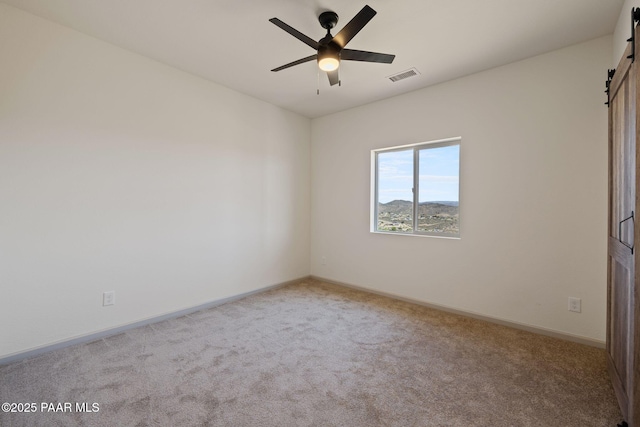 13555 E Soleil Down Rd, Mayer, AZ 86333 - unfurnished bedroom with a barn door, carpet, and ceiling fan