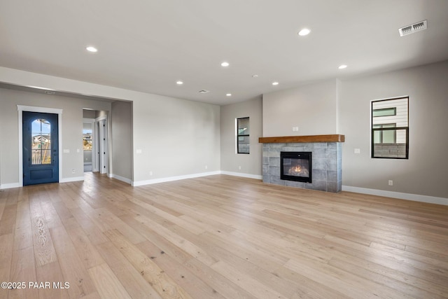 unfurnished living room with light hardwood / wood-style floors and a tiled fireplace