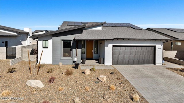 view of front facade featuring a garage, a porch, and solar panels