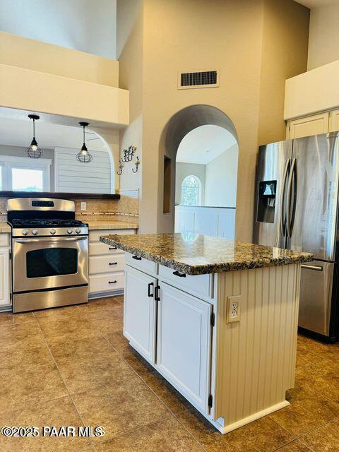 kitchen with visible vents, white cabinets, appliances with stainless steel finishes, a center island, and pendant lighting