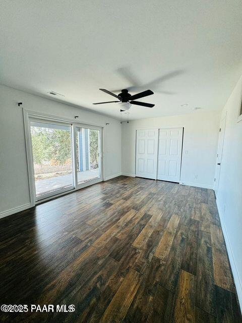 unfurnished bedroom featuring dark wood-style floors, access to outside, baseboards, and ceiling fan