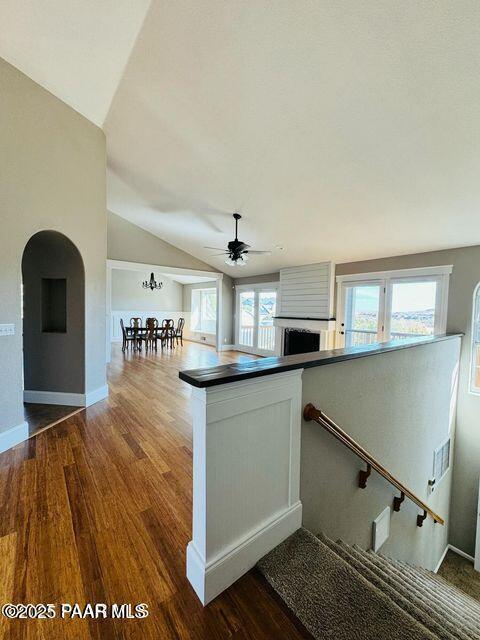 kitchen with lofted ceiling, a peninsula, dark wood-type flooring, baseboards, and dark countertops