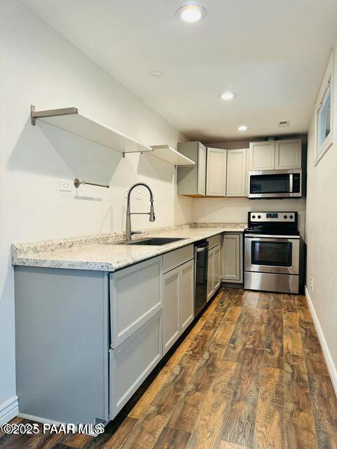 kitchen featuring appliances with stainless steel finishes, open shelves, a sink, and gray cabinetry