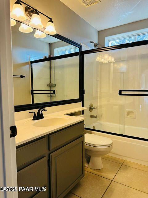 bathroom with visible vents, toilet, enclosed tub / shower combo, vanity, and tile patterned flooring