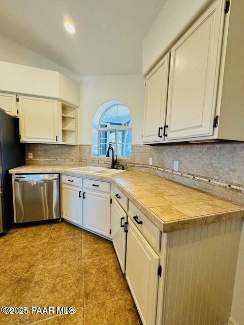 kitchen with a sink, white cabinets, stainless steel dishwasher, open shelves, and tasteful backsplash