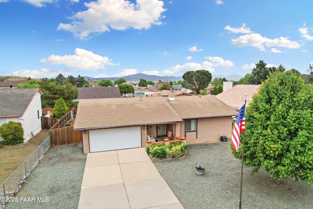 view of front of property featuring an attached garage, driveway, fence, stucco siding, and a mountain view