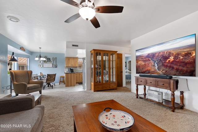 living area with light carpet, a chandelier, and ceiling fan