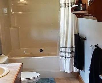 full bathroom with shower / bath combination with curtain, toilet, and vanity