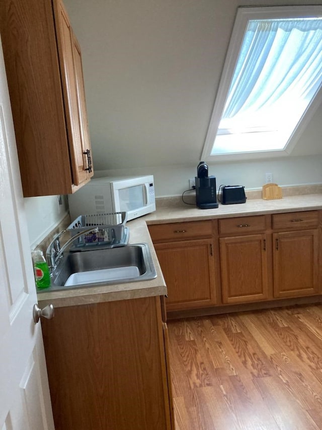 kitchen with a skylight, light hardwood / wood-style floors, and sink