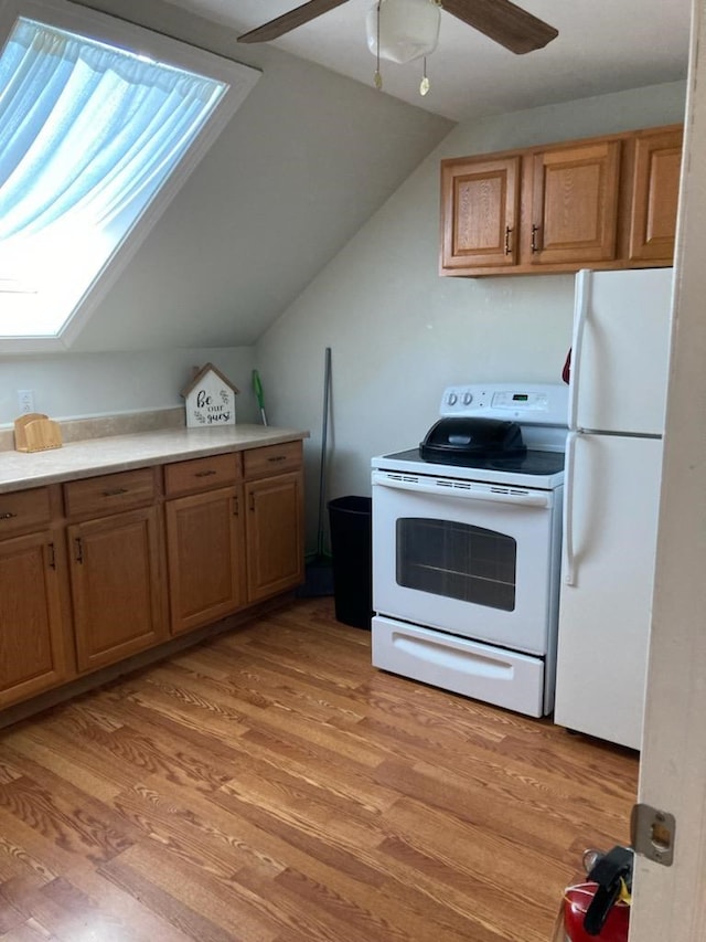 kitchen with ceiling fan, white appliances, light hardwood / wood-style floors, and vaulted ceiling with skylight