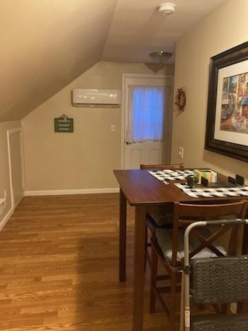 dining space with a wall mounted air conditioner, vaulted ceiling, and hardwood / wood-style flooring