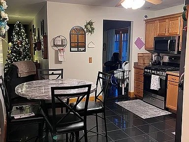 kitchen with range with gas stovetop, ceiling fan, dark tile flooring, and stone counters