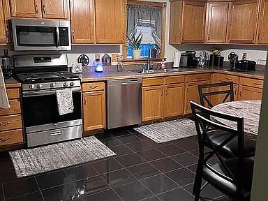 kitchen featuring appliances with stainless steel finishes, dark tile floors, and sink