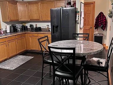 kitchen with dark tile floors and black fridge