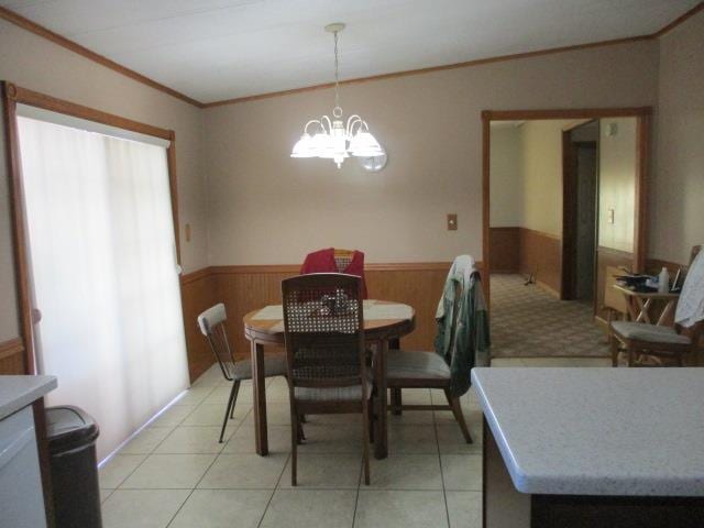 tiled dining area featuring a chandelier, crown molding, and wood walls