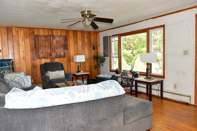 living room featuring hardwood / wood-style floors, a baseboard radiator, ceiling fan, ornamental molding, and wood walls