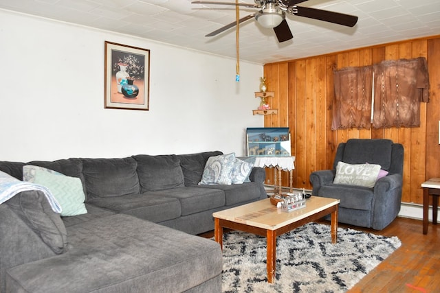 living room with ceiling fan, ornamental molding, wooden walls, and hardwood / wood-style floors