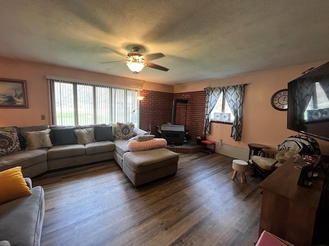 living room with hardwood / wood-style floors, a healthy amount of sunlight, a wood stove, and a textured ceiling