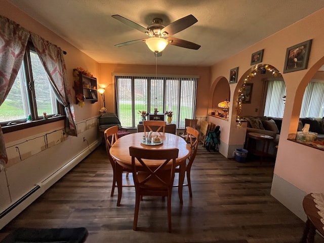 dining space featuring baseboard heating, a wealth of natural light, ceiling fan, and dark wood-type flooring